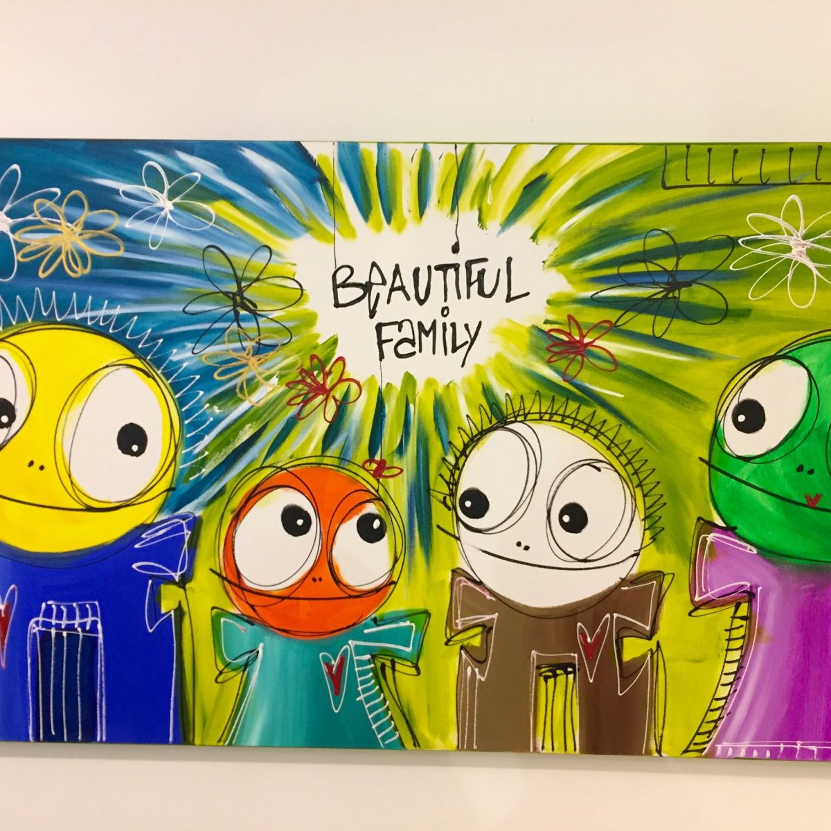 Vier bunte Figuren mit großen Augen stehen vor einem strahlenden Hintergrund mit Blumenformen. Jede Figur trägt ein Herzsymbol auf der Kleidung. Oben steht handschriftlich „BEAUTIFUL FAMILY“.